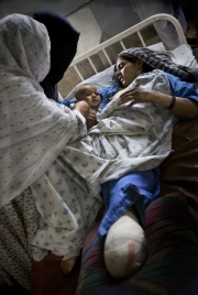 Bibi Zuhara (22) is trying to feed her four-month-old son, Amanullah. A bomb was dropped on her house, crushing everybody inside. Bibi Zuhara lost her left leg and her son is seriously injured in both legs. They are with 26 other wounded at the Metharlam hospital in Laghman. The 22d, August, 2008.